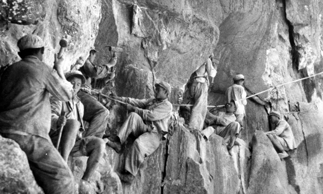 1954年，修筑康藏公路的解放軍戰(zhàn)士們在怒江兩岸的懸崖陡壁上辟山筑路。新華社稿 李萬春、張加里攝